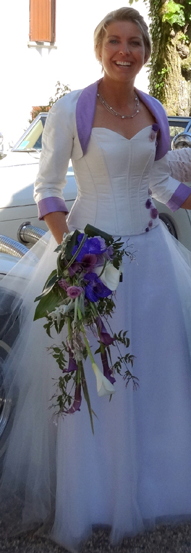 Robe de mariée blanche, bustier en doupion, fleurs parme, jupe en tulle. Boléro réversible assorti.