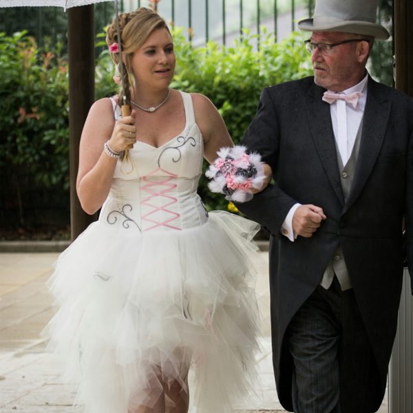 Alicia dans sa robe de mariée blanche avec des touches de rose et de gris.